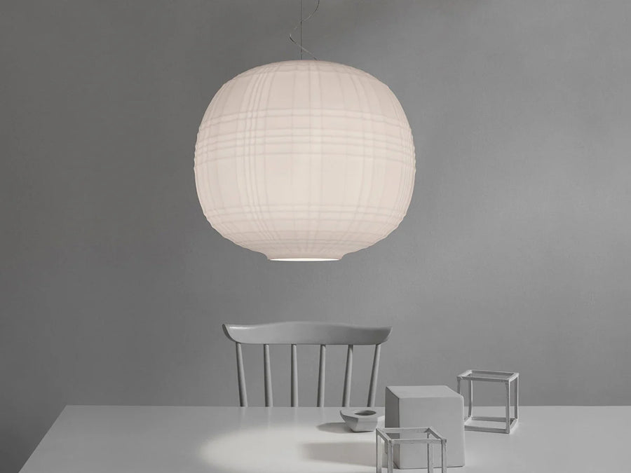 White spherical pendant lamp hanging above a minimalist table and chairs against a gray background