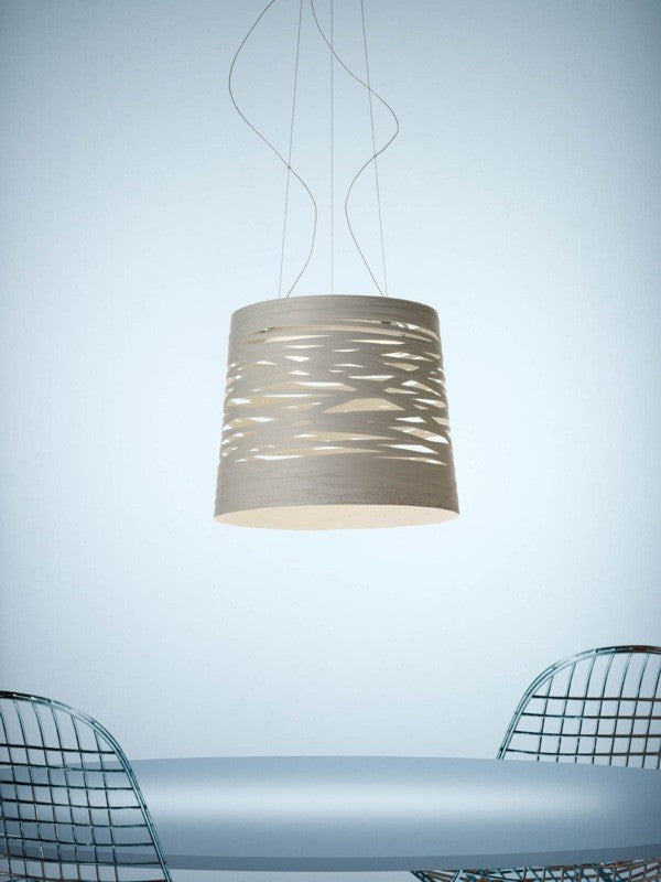 Modern pendant light hanging above a table with chairs on a light blue background