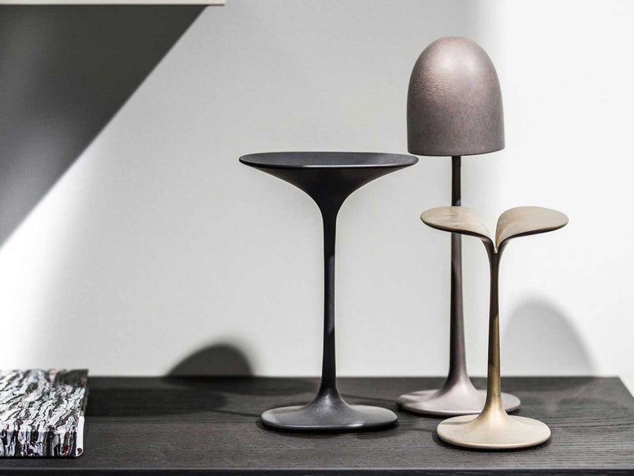 A trio of Gardeco Bronze Sculpture Mushroom Cup table lamps from the Mushrooms Collection on a table next to a book.