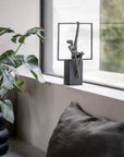 Decorative sculpture on a windowsill with a plant and cushions in the foreground.