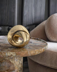 Gold decorative brass sculpture on a marble side table with a sofa in the background