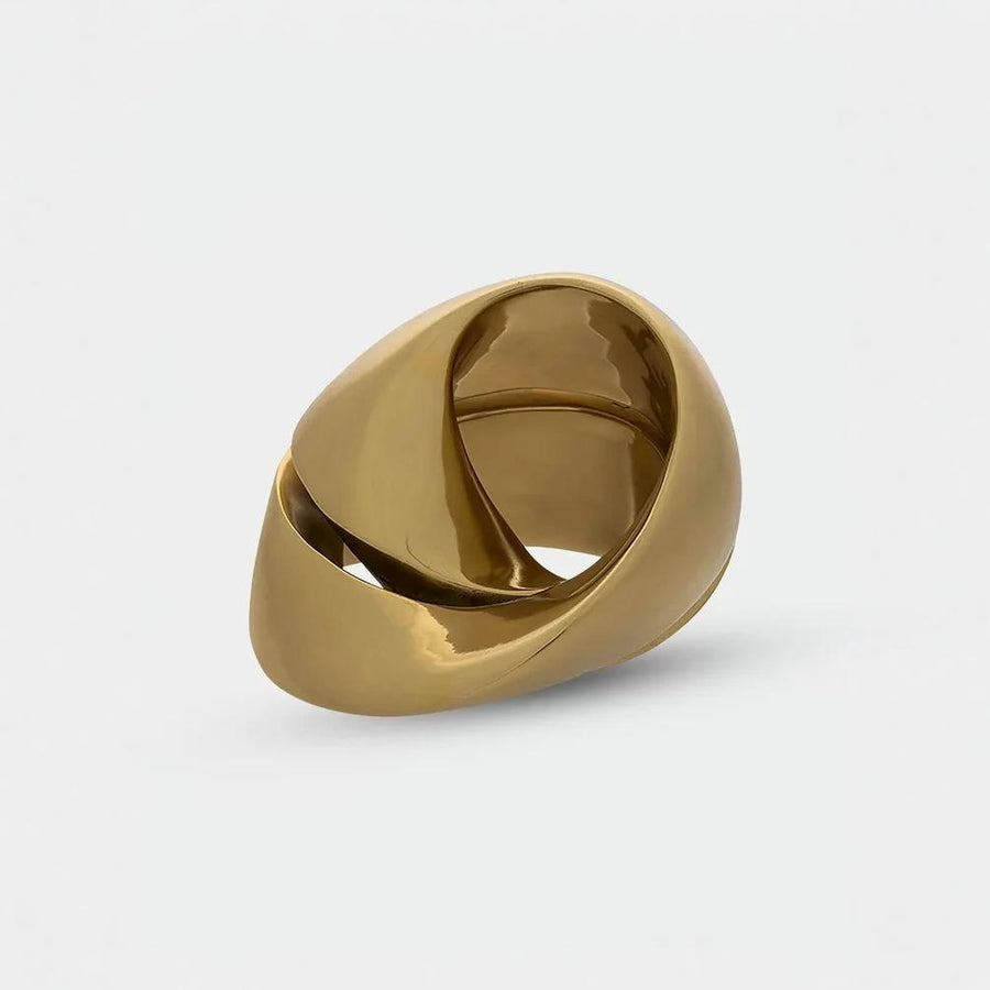 Close up of gold finish sculpture with a unique design on a light gray background