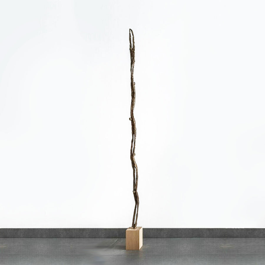 A limited edition Gardeco Bronze Sculpture Wave of a tree standing in front of a white wall, created by Ann Vrielinck.