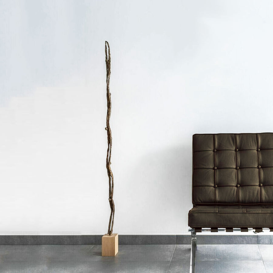 Limited edition: A Gardeco Bronze Sculpture Wave chair next to a wooden floor lamp designed by Ann Vrielinck.