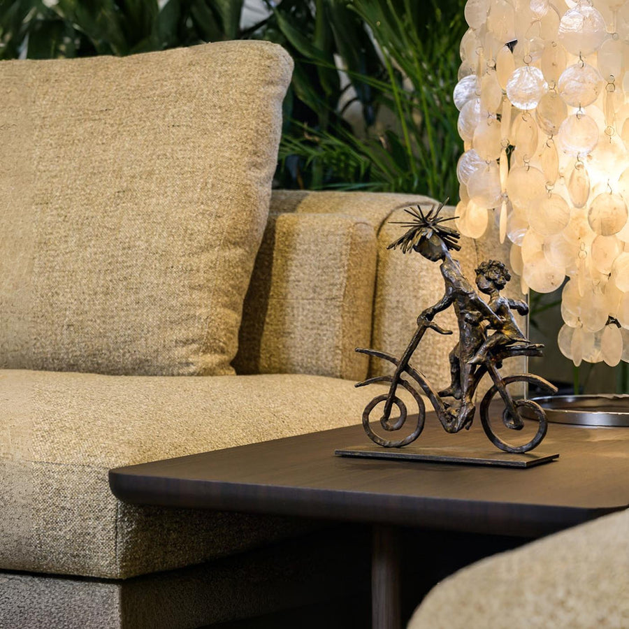 Beige sofa with decorative sculpture on a table and chandelier in the background