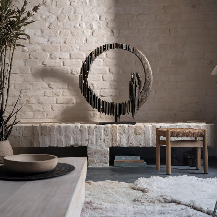 Decorative metal sculpture on a stone shelf with a rustic interior setting.