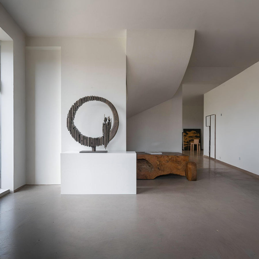 Modern interior with a sculpture on a pedestal and a textured wall.