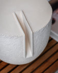 Close-up of a white ceramic object with a textured surface on a wooden surface.