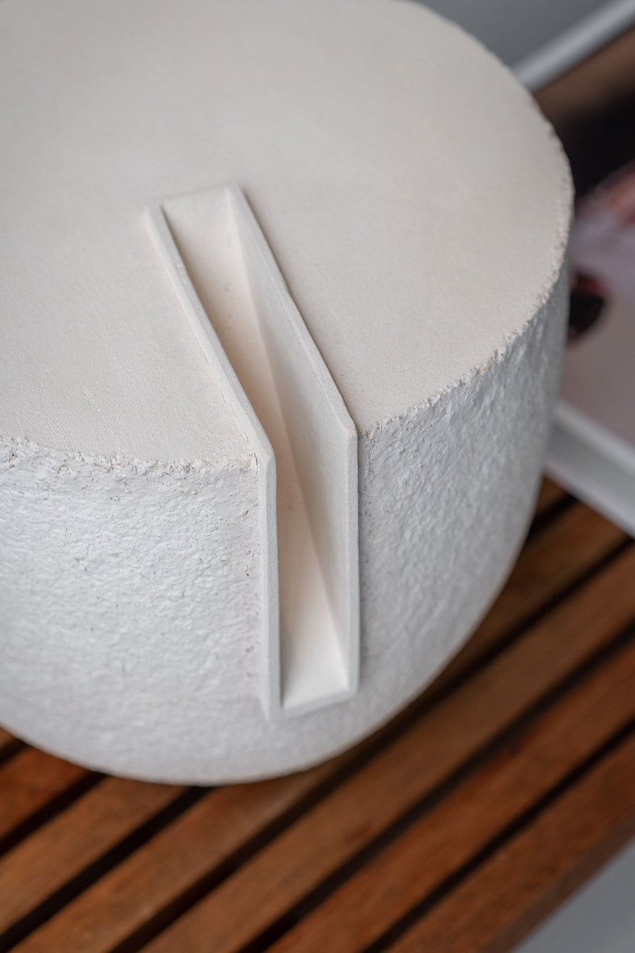 Close-up of a white ceramic object with a textured surface on a wooden surface.