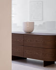 Wooden dresser with the Clausa Forma sculpture from Gardeco on top against a white wall.