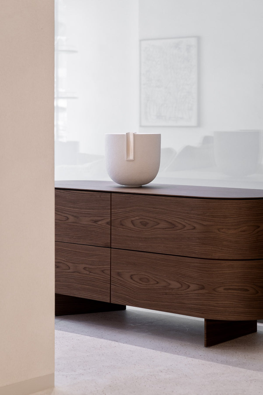 Wooden dresser with the Clausa Forma sculpture from Gardeco on top against a white wall.