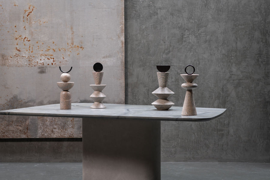 Set of stone sculptures on a table against a concrete wall.