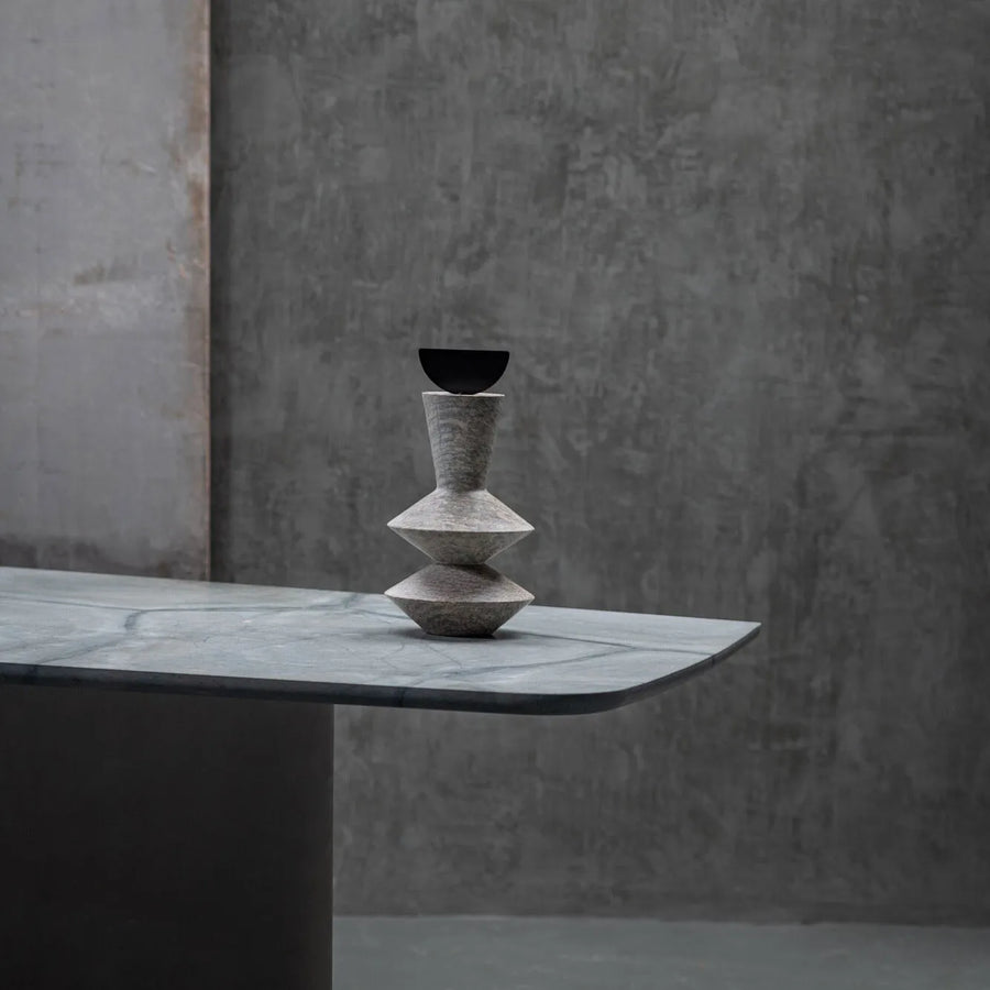 Stack of stone vases on a gray surface with a textured wall background