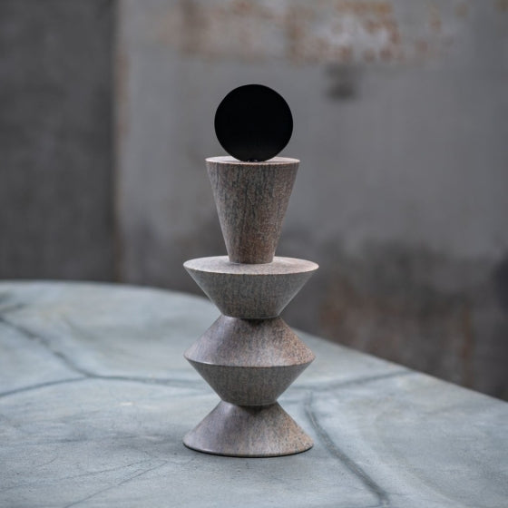A soap stone sculpture from Gardeco on a textured surface with a blurred background