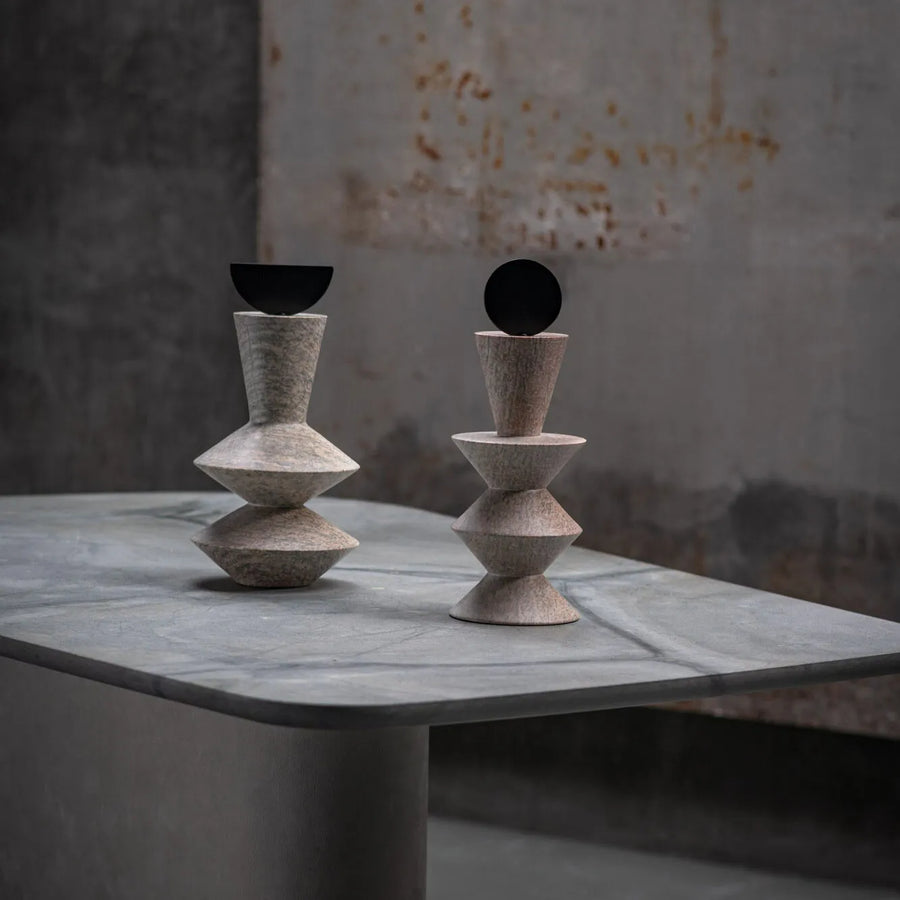 Two geometric stone sculptures on a marble surface with a rustic background
