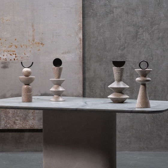 Set of four stone sculptures on a gray surface with a concrete wall background