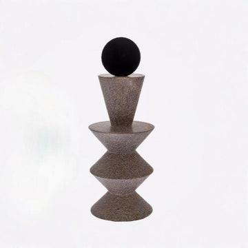 Decorative object with a black sphere on top of a textured brown pyramid structure against a white background