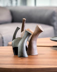 A pair of Gardeco Ceramic Sculpture Darius Black vases with ceramic figurines on a coffee table.