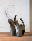 Two Gardeco Ceramic Sculpture Darius Brown, reminiscent of ceramic figurines, beautifully placed on a wooden table.