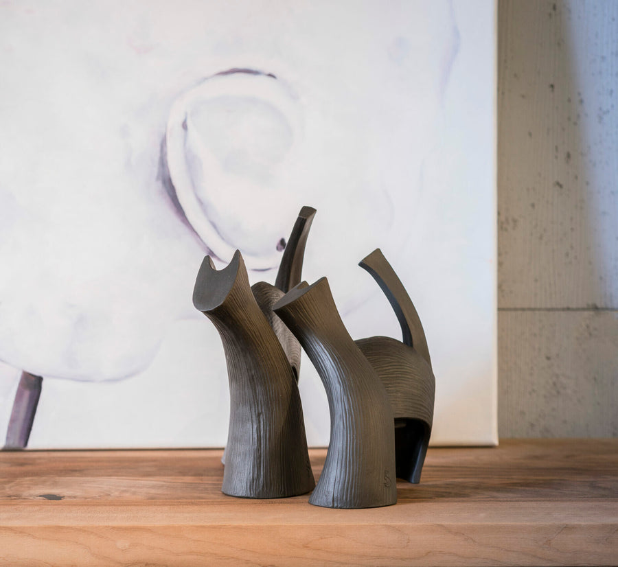 Two Gardeco Ceramic Sculpture Darius Brown, reminiscent of ceramic figurines, beautifully placed on a wooden table.