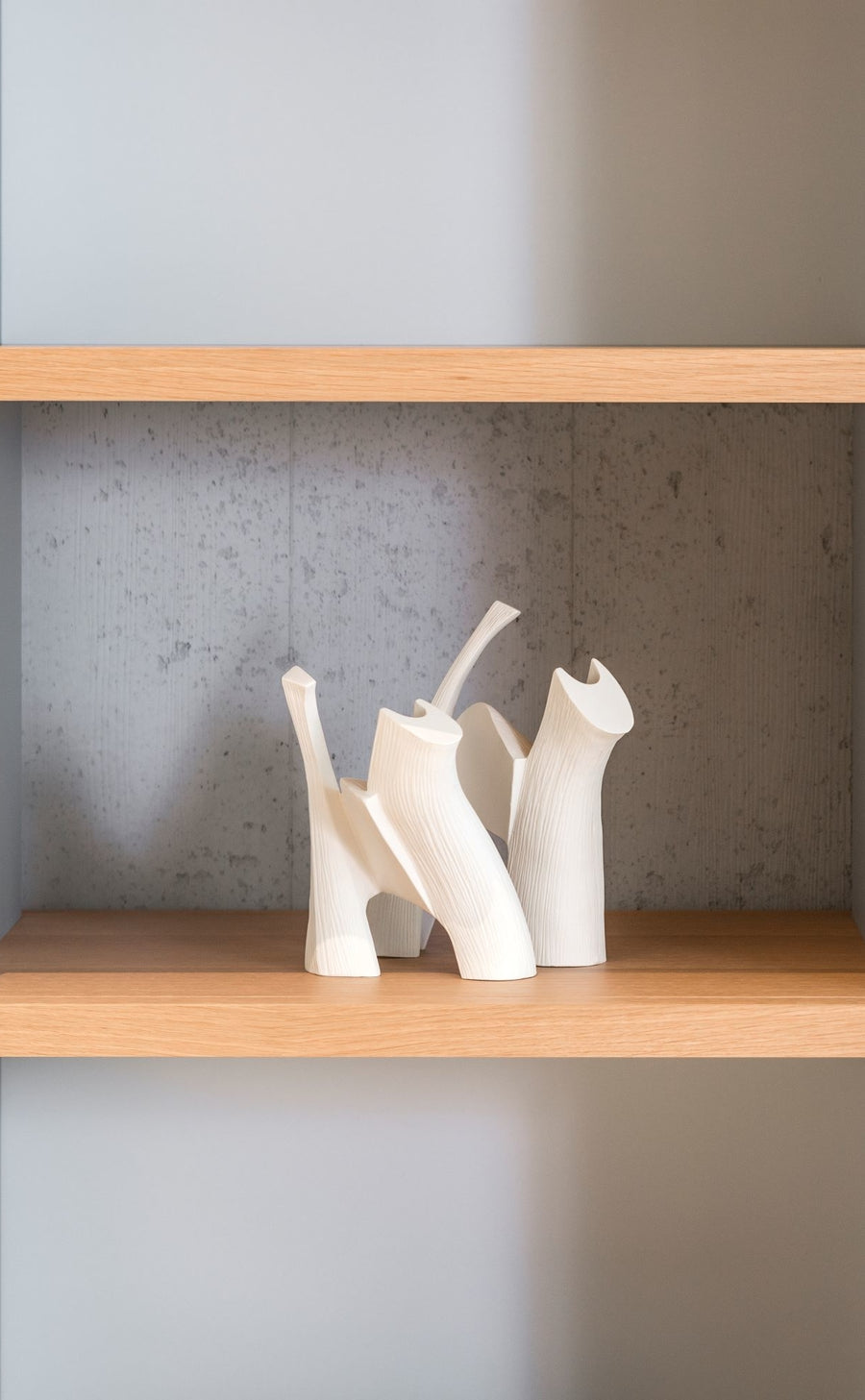 Two Gardeco Ceramic Sculpture Darius White figurines on a shelf in a bookcase.