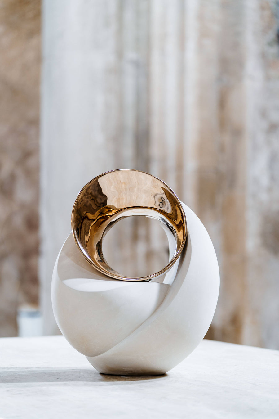 Decorative sculpture with gold and white design on a neutral background
