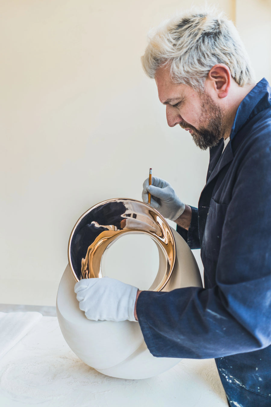 Man working on a ceramic piece with gold finish bronze inlay