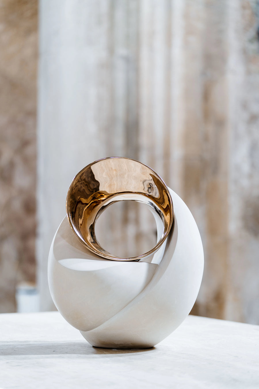 Decorative sculpture with gold and white design on a neutral background