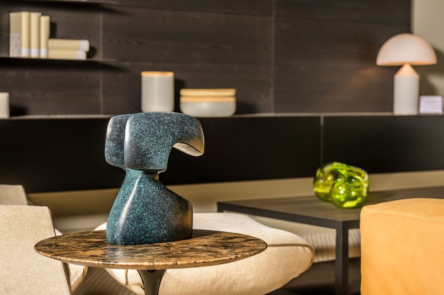 Decorative blue green patina finish bronze sculpture on a table in a modern interior setting