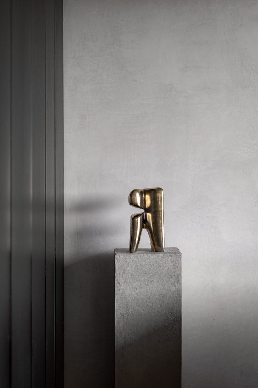 Bronze sculpture on a gray pedestal against a gray wall