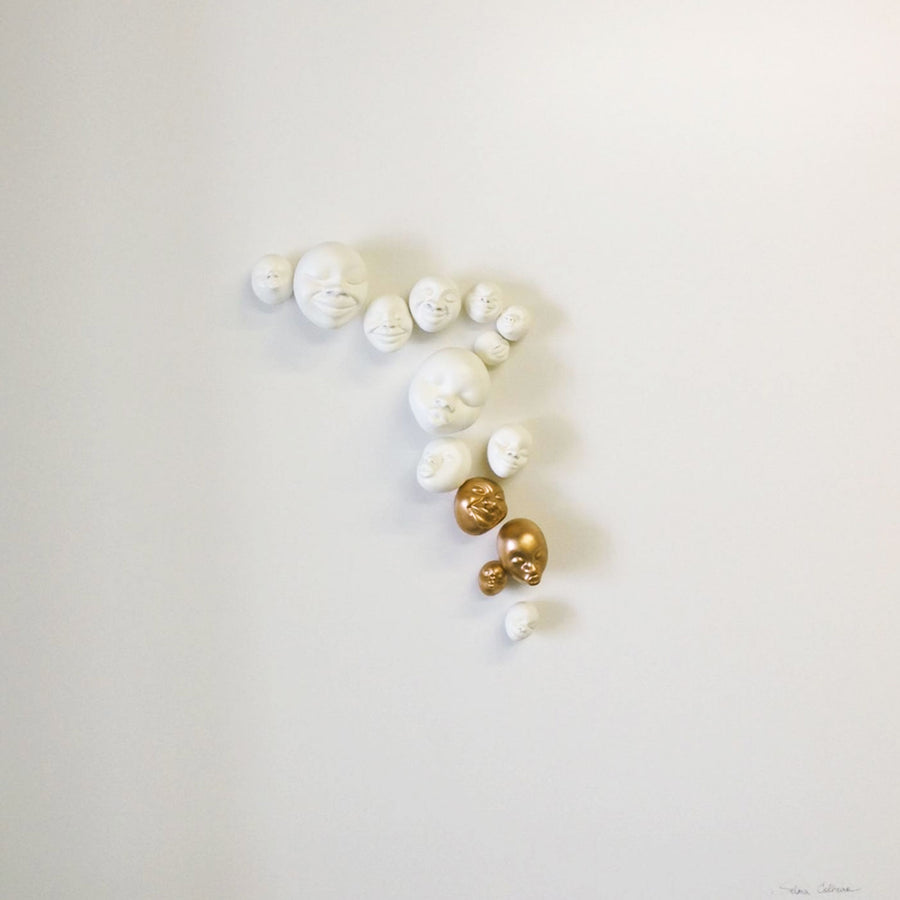 A group of Gardeco Wall Sculpture Happy Faces on a white surface, created by Brazilian ceramist Selma Calheira.