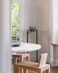 Dining area with a round white table and wooden chairs near a window and bronze sculpture of 3 men called Let's talk from Gardeco