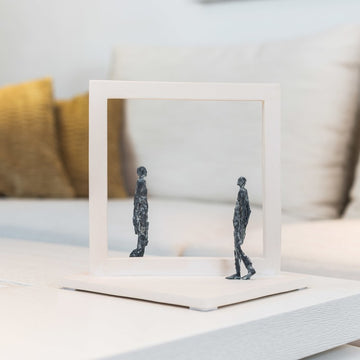 A stone and bronze sculpture showing 2 people styled on a coffee table