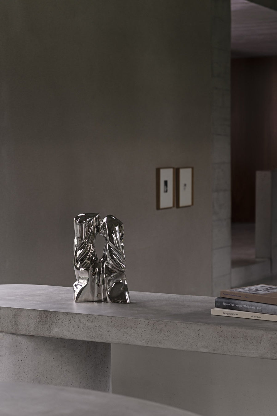 Silver abstract sculpture on a concrete surface with a neutral background
