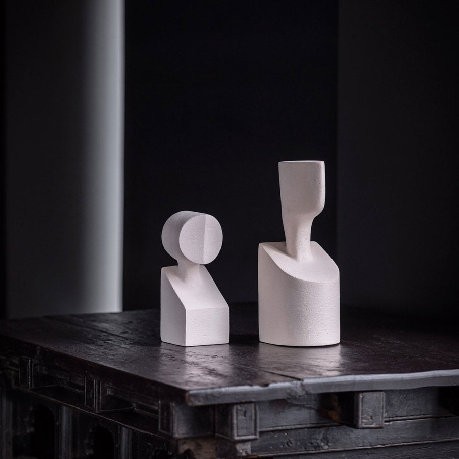 Two white ceramic vases inspired by Greek mythology and resembling Gardeco Ceramic Sculpture The Muses Plus Urania White, sitting on a table.