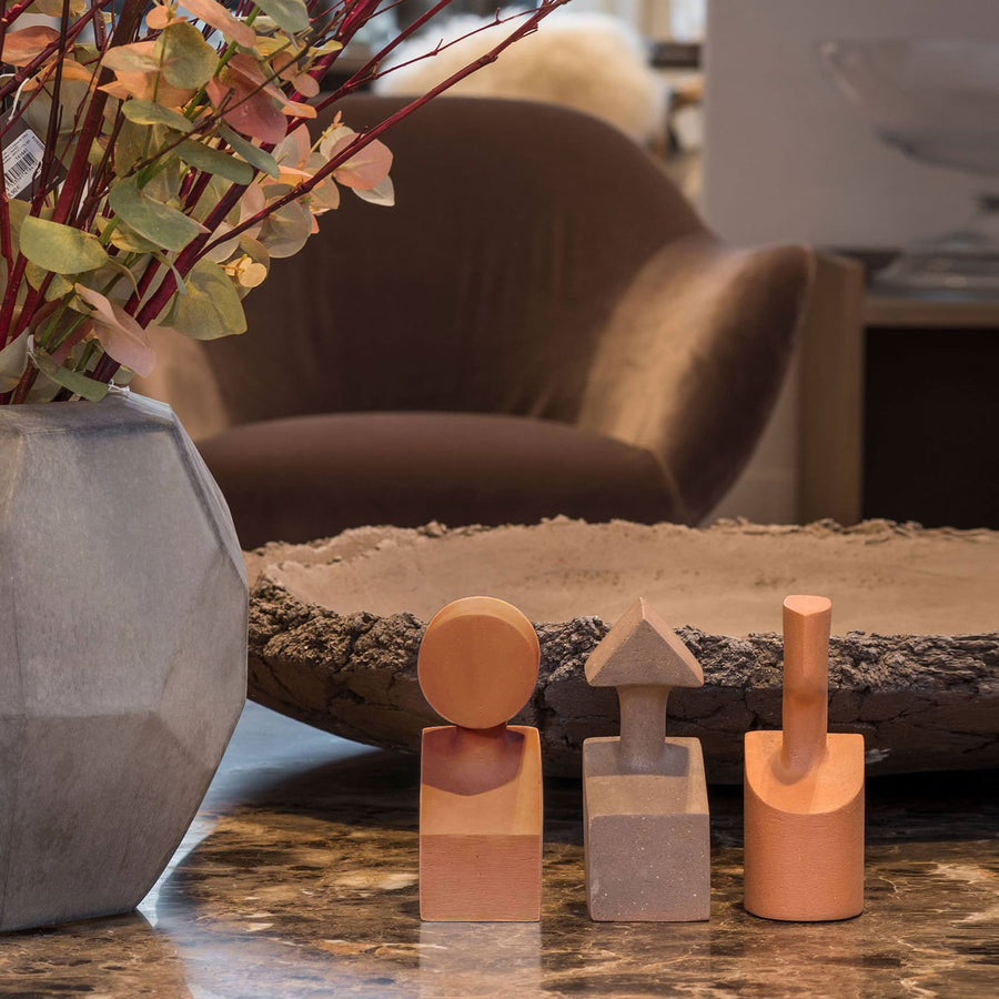 A vase of flowers sits on a table in a living room, accompanied by the Gardeco Ceramic Sculpture The Muses Small Clio Ochre.