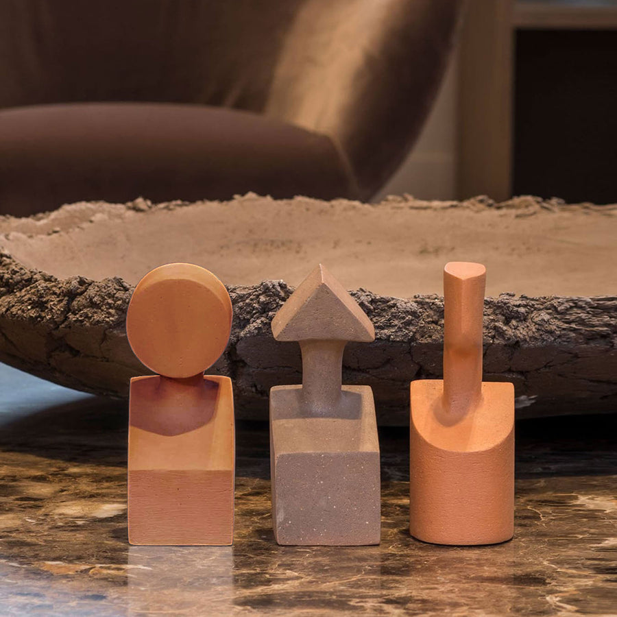 Three Gardeco Ceramic Sculpture The Muses Small Clio Ochre sit on a table next to a bowl, featuring an Ochre Finish.