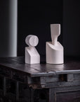 Two Gardeco Ceramic Sculpture The Muses Small Clio White vases sit on a table in a dark room.