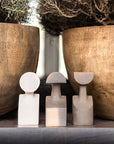 Three Gardeco Ceramic Sculpture The Muses Small Erato Natural, adorned with a natural finish, grace a table alongside a potted plant.