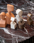 A collection of Gardeco Ceramic Sculpture The Muses Large Urania Ochre figurines, elegantly displayed on a marble table.