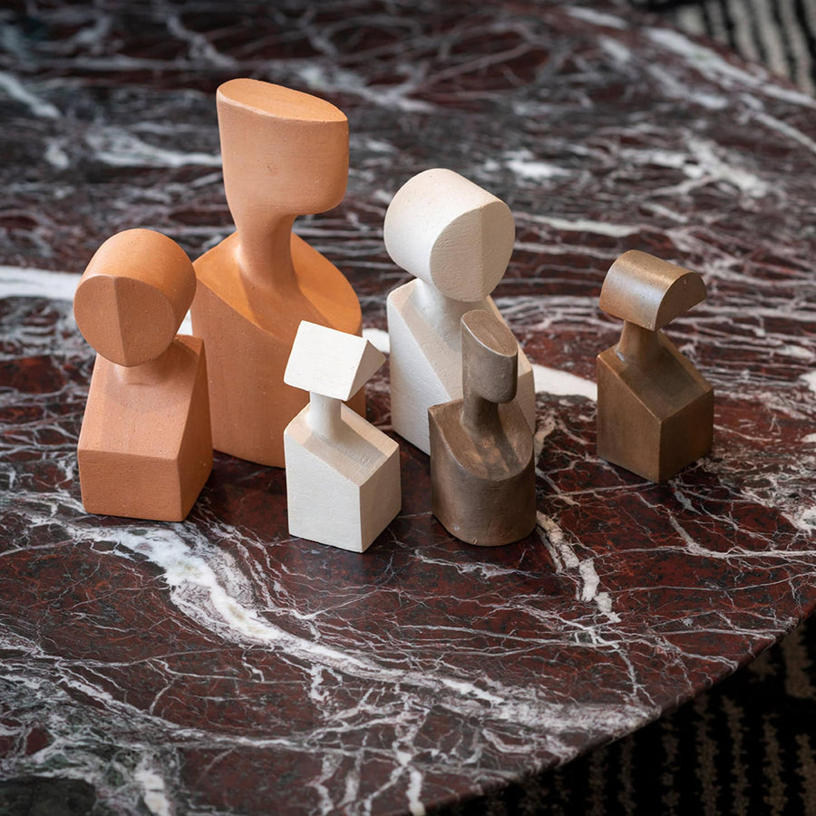 A collection of Gardeco Ceramic Sculpture The Muses Large Urania Ochre figurines, elegantly displayed on a marble table.