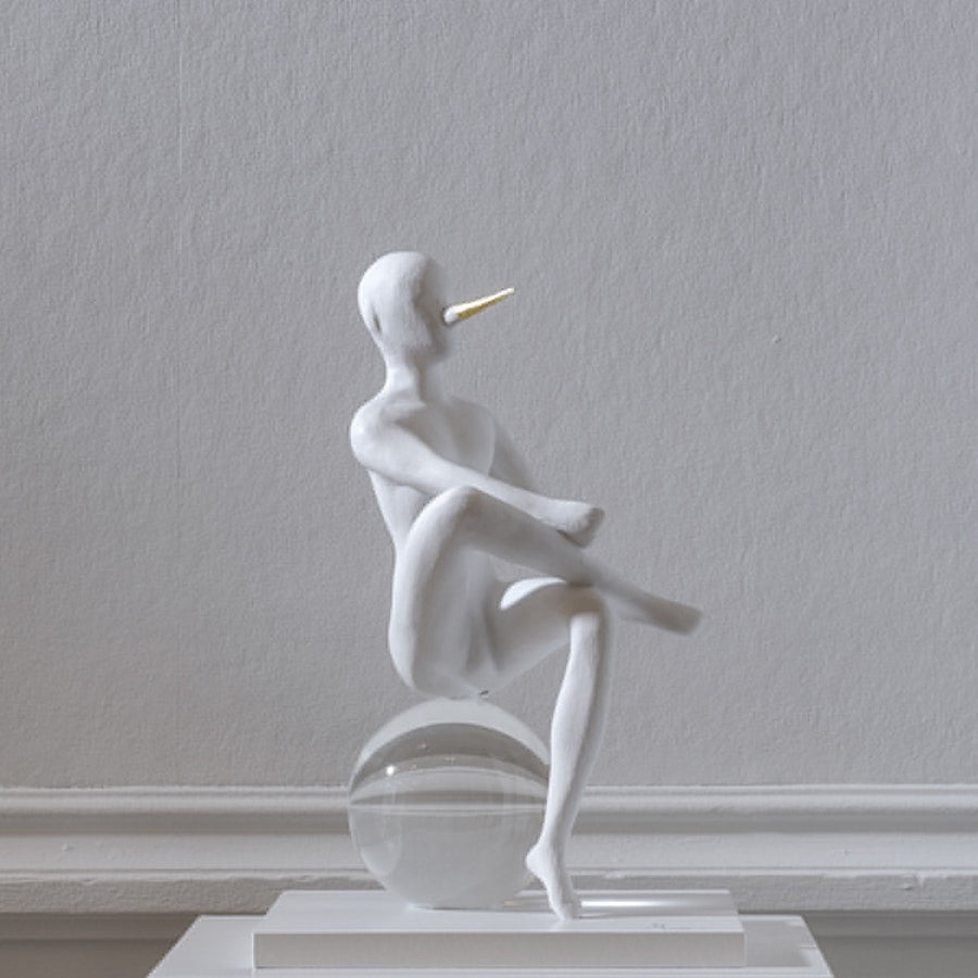 White sculpture - The Pinochhio from Gardeco on a clear sphere against a plain wall.