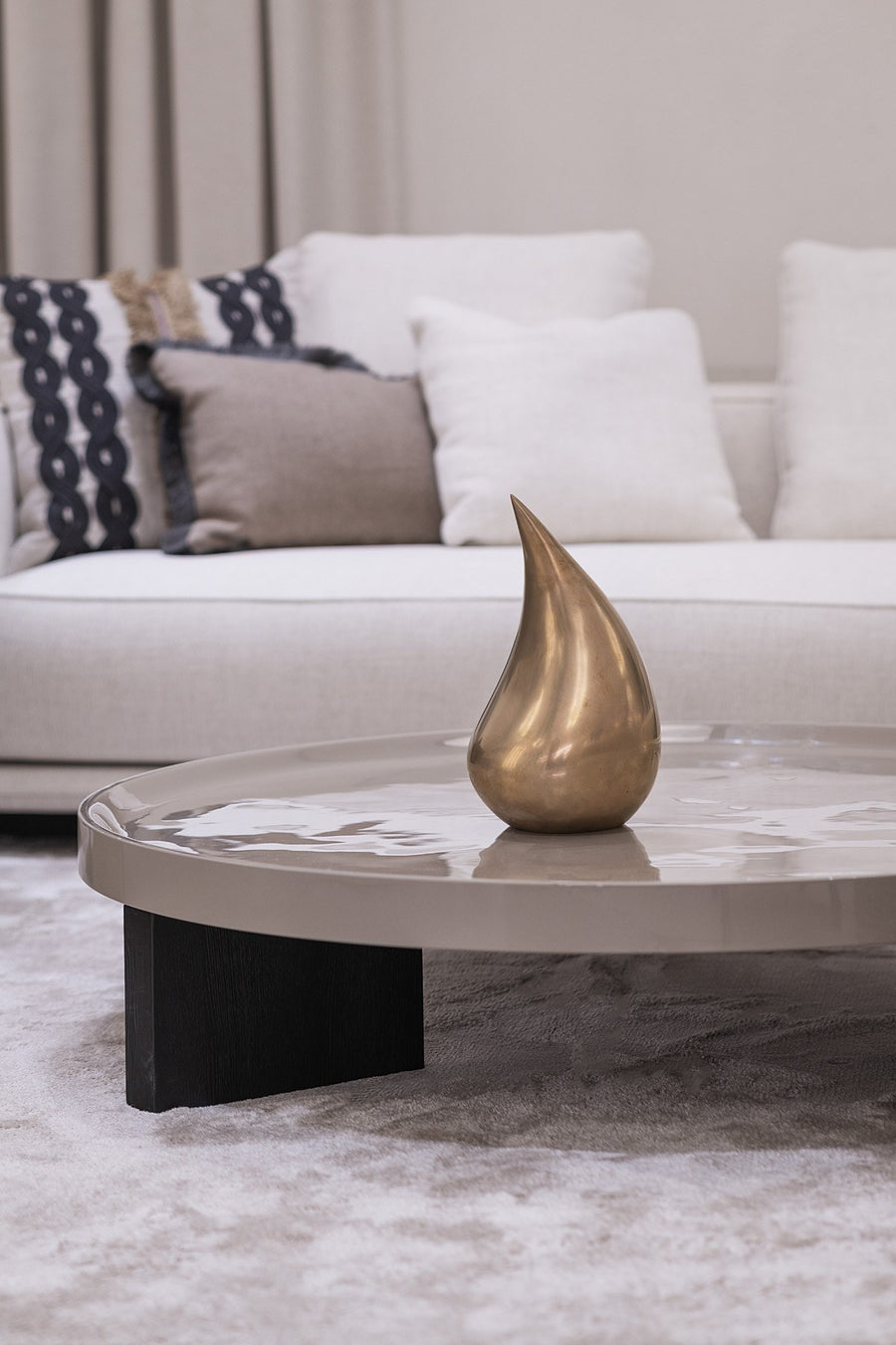 Modern living room with a marble coffee table and decorative teardrop sculpture.