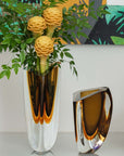 An exquisite vase with elegant flowers and a Gardeco Glass Vase Triangle 4 Fume Amber on a table.