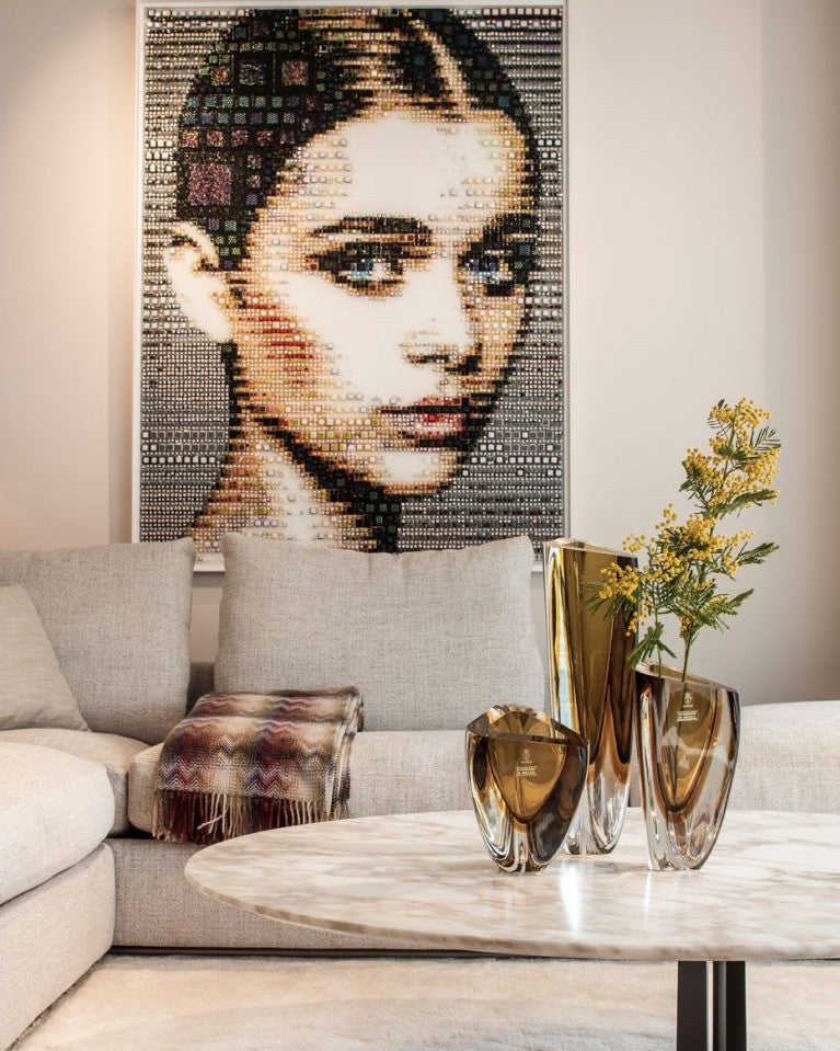 An elegant table adorned with Gardeco Glass Vase Triangle 4 Fume Amber, featuring a captivating picture of a woman's face.