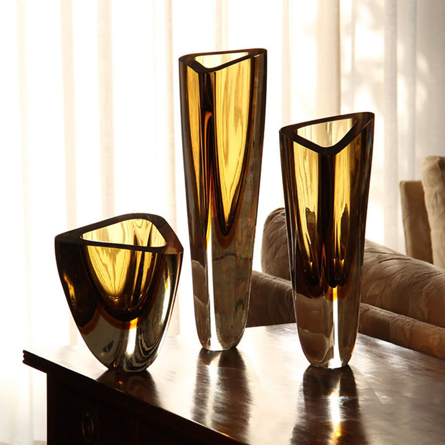 A group of Gardeco Glass Vase Triangle 4 Fume Amber objects on a table.