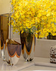 An exquisite Gardeco Glass Vase Triangle 4 Fume Amber with elegant yellow flowers.