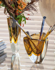 An exquisite Gardeco Glass Vase Triangle 4 Fume Amber filled with a collection of paint brushes.