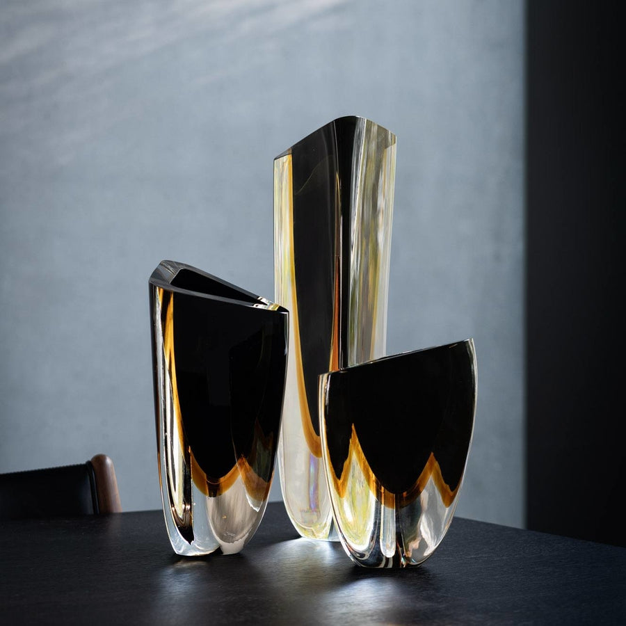 A group of Gardeco Glass Vase Triangle 1 Black Amber vases with bicolour glass on a table.