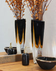 A contemporary refinement of the Gardeco Glass Vase Triangle 1 Black Amber with dried flowers, featuring bicolour glass.